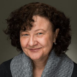 Headshot of Mel Drake, a middle aged woman with curly hair and a kind smile.